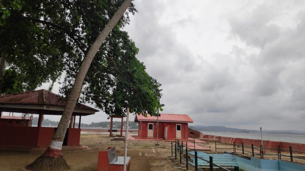Coastal sitting area on Neil Island Andaman with red shelters and cloudy sky overlooking the sea