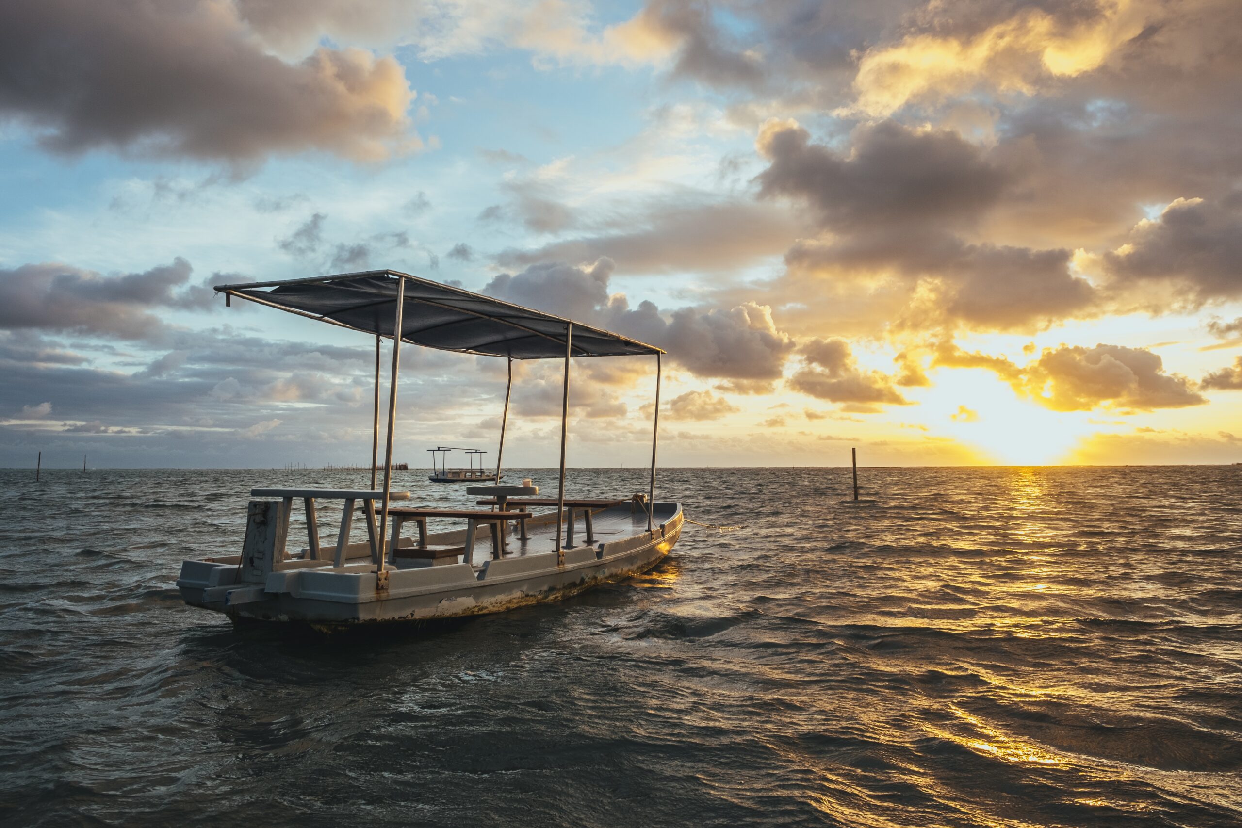 Small ferry boat sailing on the Andaman Sea during sunrise, representing the journey from Port Blair to Havelock Island.